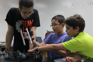 Monchini  helps two students from Horace Mann figure out how to complete the machine they have been working on. 