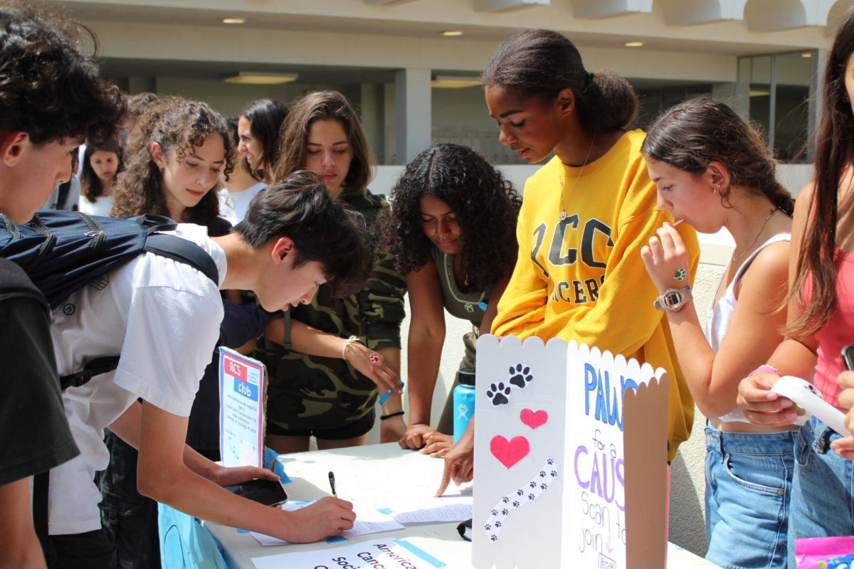 Students huddle around various booths to sign up for clubs.
