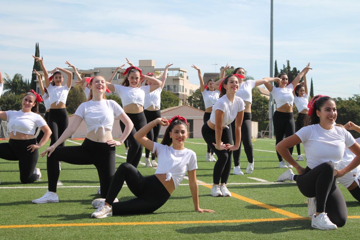 Dance company finishes their pep rally performance with a striking pose and a big smile.
