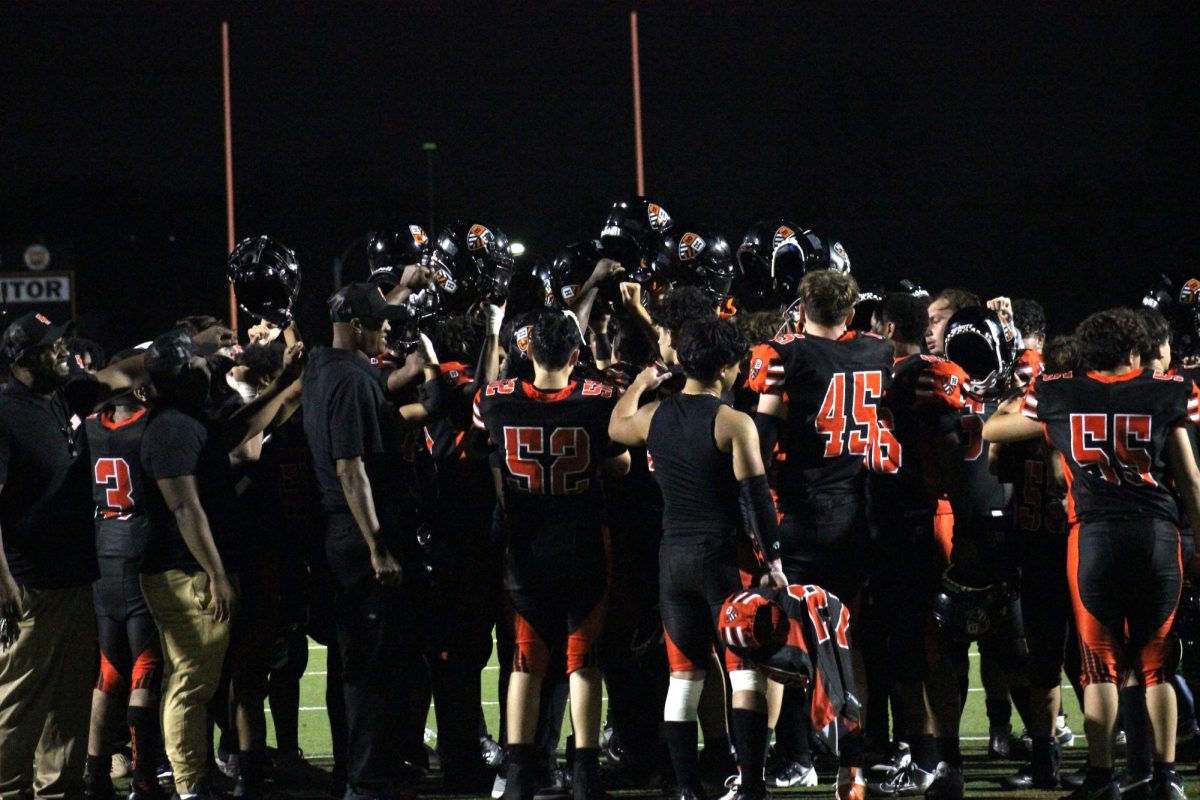 The football team and coaches celebrate their first win and game of the season.