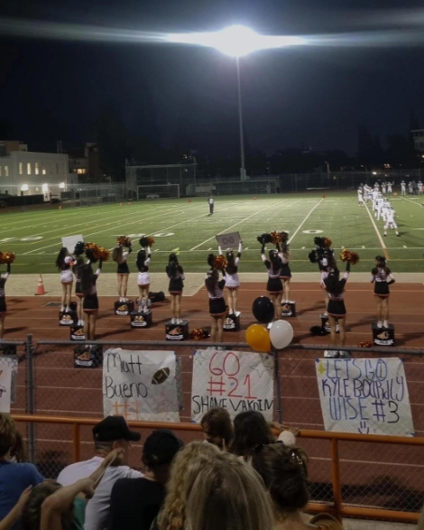 Cheerleaders cheer at senior night football game.
