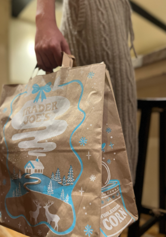 A student holds a paper shopping bag from Trader Joe's.